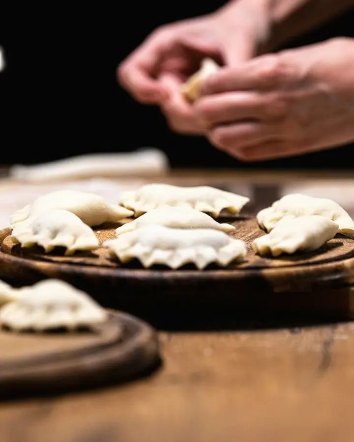 Ręce lepią pierogi na drewnianym stole